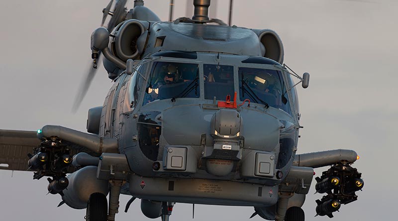 An embarked MH-60 Romeo helicopter prepares to land onboard HMAS Adelaide at sunset during First Of Class Flight Trials. Photo by Able Seaman Jarrod Mulvihill.