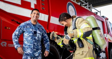 Air Force Indigenous Youth program participant Tallira Hopkins tries on the firefighter uniform with firefighter Leading Aircraftman Ray Solinas at RAAF Base Amberley, Queensland. Story by Flight Lieutenant Suellen Heath. Photo by Leading Aircraftwoman Kate Czerny.