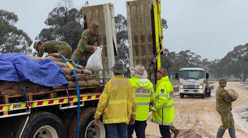 Soldiers from the 2nd/14th Light Horse Regiment (Queensland Mounted Infantry) help the NSW Rural Fire Service to unload sand bags near Deniliquin, NSW, as part of Operation Flood Assist 22-2. Photo supplied.