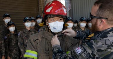 Warrant Officer Tristan Smith, right, assists a midshipman from the Republic of Korea Navy get into a fire suit at the Royal Australian Navy School of Survivability and Ship Safety in Jervis Bay, NSW. Story by Lieutenant Nancy Cotton. Photo by Leading Seaman Ryan Tascas.