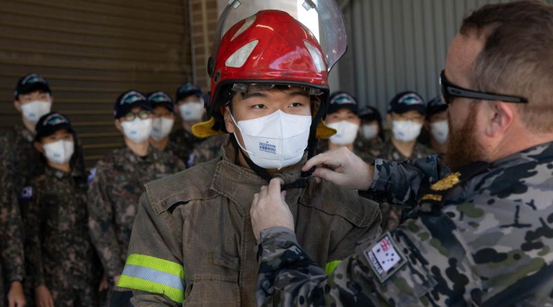 Warrant Officer Tristan Smith, right, assists a midshipman from the Republic of Korea Navy get into a fire suit at the Royal Australian Navy School of Survivability and Ship Safety in Jervis Bay, NSW. Story by Lieutenant Nancy Cotton. Photo by Leading Seaman Ryan Tascas.