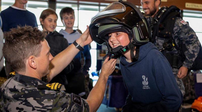 Lieutenant Joel Woods from Clearance Diver Team Four helps Dodhi with a bomb suit helmet during his tour at the Fremantle Ports Maritime Day in Western Australia. Photo by Leading Seaman Ernesto Sanchez.