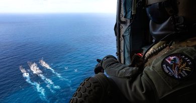 Leading Seaman Nathan Cox watches out of HMAS Arunta's embarked MH-60R helicopter "Athena" as HMAS Arunta (right) and USS Milius conduct a duel Replenishment at Sea with JS Oumi during Exercise Malabar 2022. Photo by Leading Seaman Susan Mossop.