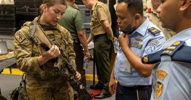 Australian Army signaller Christie Dutra shows members from the Indonesian National Armed Forces the Austeyr Enhanced F88 at HMAS Adelaide’s Defence Industry Expo. Story by Lieutenant Amy Johnson. Photo by Leading Seaman Nadav Harel.
