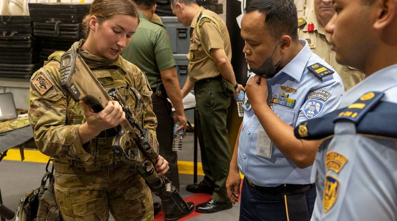 Australian Army signaller Christie Dutra shows members from the Indonesian National Armed Forces the Austeyr Enhanced F88 at HMAS Adelaide’s Defence Industry Expo. Story by Lieutenant Amy Johnson. Photo by Leading Seaman Nadav Harel.