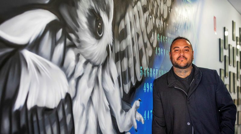 Artist and Ngarrindjeri man Thomas Readett stands beside his artwork at 462 Squadron Headquarters. Story by Flight Lieutenant Rob Hodgson. Photo by Leading Aircraftman Sam Price.