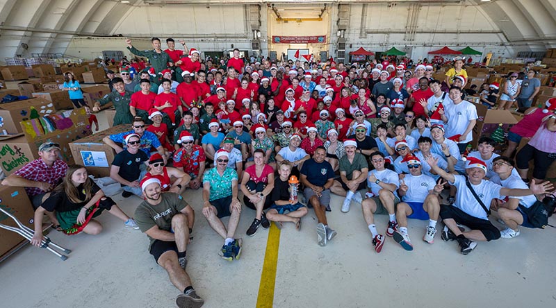 International participants from the United States, Japan, Australia, New Zealand and Republic of Korea, take time out from packing parachute bundles during Operation Christmas Drop's Bundle Build Day. Photo by Yasuo Osakabe.