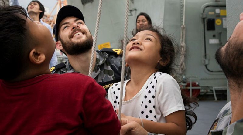 Lieutenant Quaelan Brooks helps children from the Khlong Toey slum raise communication flags on HMAS Anzac during a port visit to Bangkok in 2018. Story by Corporal Michael Rogers. Photo by Petty Officer Kayla Jackson.