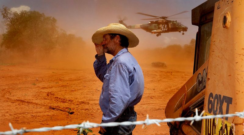 Jack Andrews, Station Manager at Yeeda Station, shelters from the dust as an MRH-90 Taipan delivers animal feed. Photos by Leading Aircraftwoman Kate Czerny. Story by Flight Lieutenant Dean Squire.