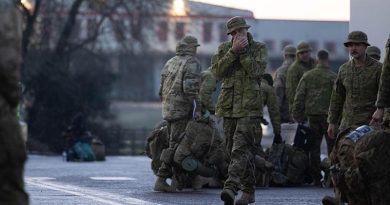 An Australian Army soldier from the 5th Battalion, Royal Australian Regiment, warms his hands during loading of bags and stores onto transport after arriving into the United Kingdom as part of Operation Kudu. Photo by Corporal Jonathan Goedhart.