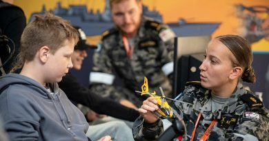 Able Seaman Aviation Technician – Aircraft Casey Anderson assists a member of the public with a Royal Australian Navy Fleet Air Arm flight simulator inside the RAN exhibition tent the 2023 Avalon International Airshow. Story by Lieutenant Ben Willee. Photo by Corporal David Cotton.