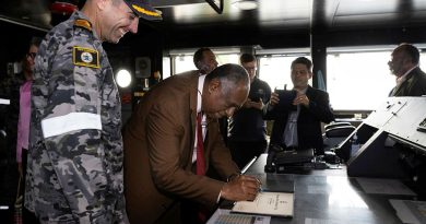 The Prime Minister of Vanuatu Alatoi Ishmael Kalsakau Ma’aukora, centre, signs the welcome book during a tour of HMAS Canberra. Story by Lieutenant Geoff Long. Photo by Leading Seaman Daniel Goodman.