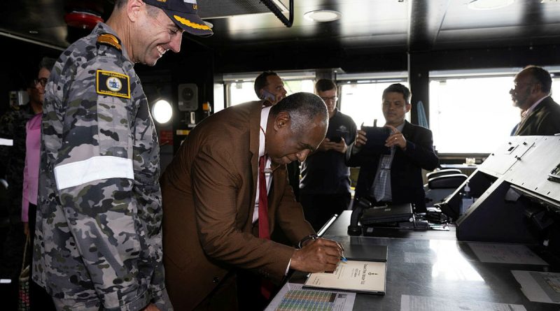 The Prime Minister of Vanuatu Alatoi Ishmael Kalsakau Ma’aukora, centre, signs the welcome book during a tour of HMAS Canberra. Story by Lieutenant Geoff Long. Photo by Leading Seaman Daniel Goodman.