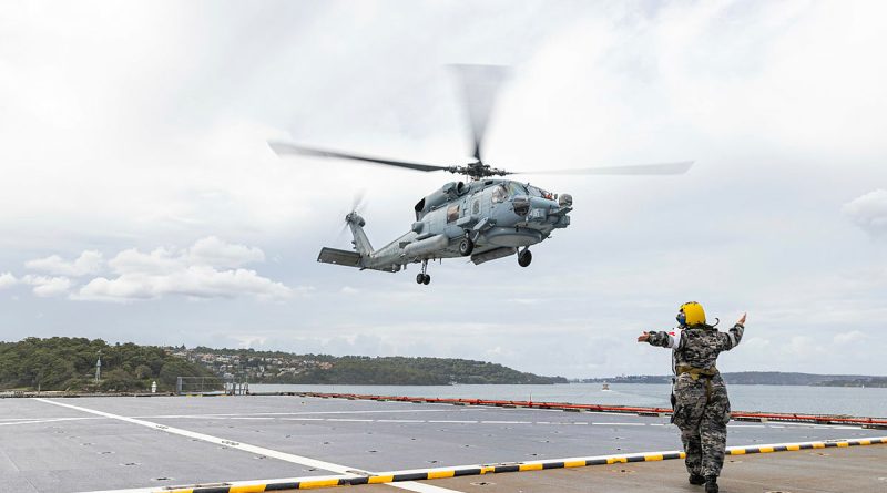 HMAS Choules' flight deck marshaller directs an MH-60R helicopter to the flight deck. Story by Petty Officer Helen Frank. Photo by Able Seaman jasmine Moody.