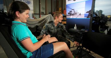 Seaman Liam Cox, from HMAS Albatross, guides eight-year-old Kira on the Navy helicopter simulator display at the Hunter Valley Airshow. Story by Flight Lieutenant Thomas McCoy. Photo by Sergeant Glen McCarthy.
