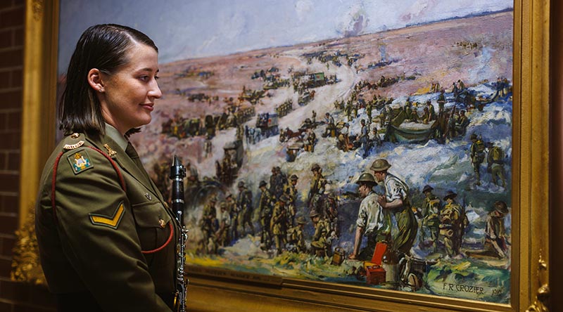 Australian Army Band member Lance Corporal Lenore Evans with a painting by her great-great-great-uncle, War Artist Frank Crozier who served at Gallipoli and in France. The painting is held by the Australian War Memorial at the Treloar Technology Centre, Canberra. Photo by Sergeant Oliver Carter.