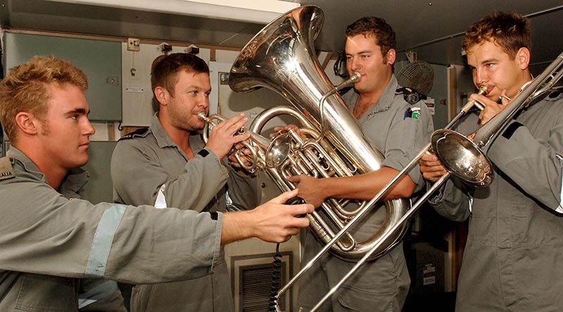 Members from the Navy Band provide the early morning Wakey Wakey call to ships company onboard HMAS Tobruk to the sounding tunes of Happy Birthday, as Able Seaman Ryan Innes holds the mic for Able Seamen Marcus Salone, Adam Arnold and Troy Ottens.