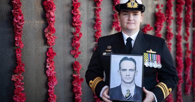 Lieutenant Commander Ashleigh Payne holds a picture of her great-uncle Leading Aircraftman James Geoffrey Payne in front of the Roll of Honour at the Australian War Memorial. Photo by Corporal Michael Rogers.