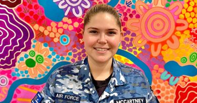 Flight Lieutenant Aimee McCartney stands before her painting titled ‘Nawu’ - one of the many traditional artworks now on display at her first solo exhibition in Melbourne.