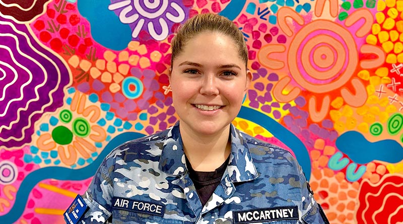Flight Lieutenant Aimee McCartney stands before her painting titled ‘Nawu’ - one of the many traditional artworks now on display at her first solo exhibition in Melbourne.