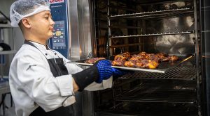 Chef Bikendra Tamang takes fresh chicken tandoori from the oven during a cooking class for Operation Accordion personnel at Australia’s operating base in the Middle East. Photo by Corporal Melina Young.