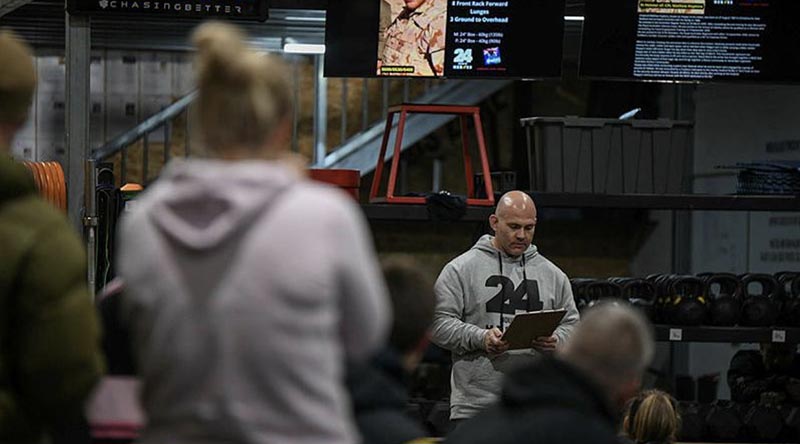 Warrant Officer Class 2 Beau Thomas reads the biography of a fallen soldier before another workout begins at the 24 Hours of Heroes fundraiser for Wounded Heroes. Photo by TrewBella Photography.