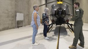 Lieutenant Jack Breckmann briefs winners of the Variety flight simulator experience, Paula Jeff and Heather Fripp, on the EC-135 helicopter during a tour of 723 Squadron, HMAS Albatross. Photo by Petty Officer Kayla Jackson.