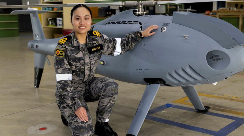 Lieutenant Fiona Nguyen in front of a Shiebel S-100 air vehicle at 822X Squadron, HMAS Albatross. Story by Captain Karam Louli. Photo by Petty Officer Justin Brown.