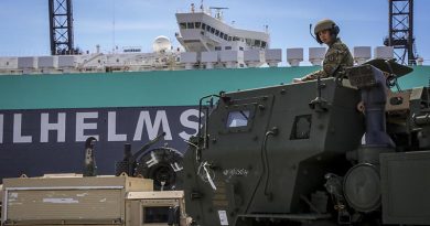 A HIMARS crewmember with the US Army's 17th Field Artillery Brigade guides his vehicle at the Port of Tacoma, Washington, before loading on a ship bound for Australia. US Army photo by Sergeant Joshua Oh.