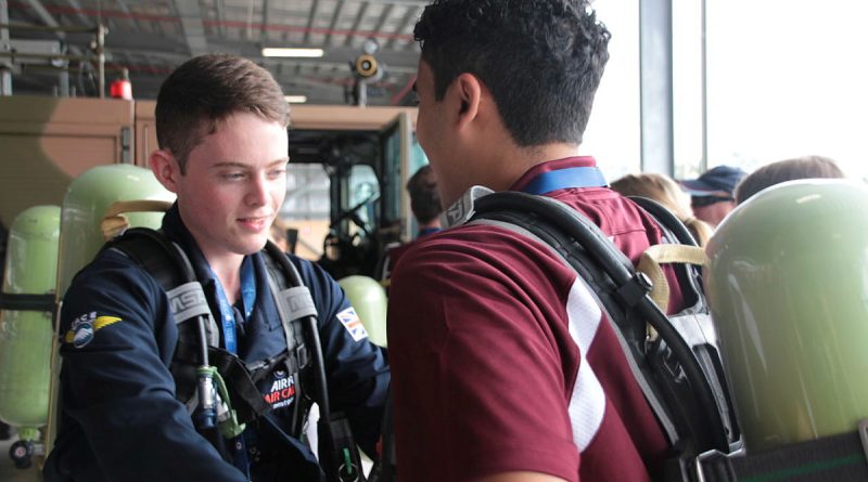 UK Air Cadet Alex Athey helps United States Air Cadet Ishan Swali into his breathing gear at an information session on flight line fire suppression at 23 Squadron during their visit. Story by Flight Lieutenant Julia Ravell.