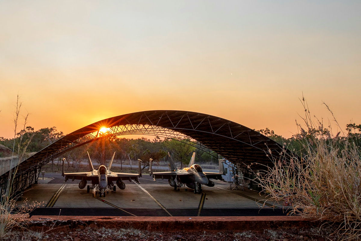 The sun sets behind two Royal Australian Air Force F/A-18F Super Hornets in the Ordnance Loading Area at RAAF Base Tindal, Northern Territory, during Exercise Talisman Sabre 2023. Story by Flight Lieutenant Claire Campbell. Photo by Leading Aircraftwoman Annika Smit.