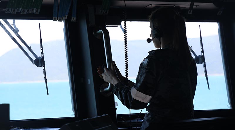 A Royal Australian Navy sailor on the bridge of HMAS Brisbane keeps watch during search operations for the crashed MRH-90 in the vicinity of Lindeman Island during Exercise Talisman Sabre 23. Photo by Leading Seaman Hannah Linsley.