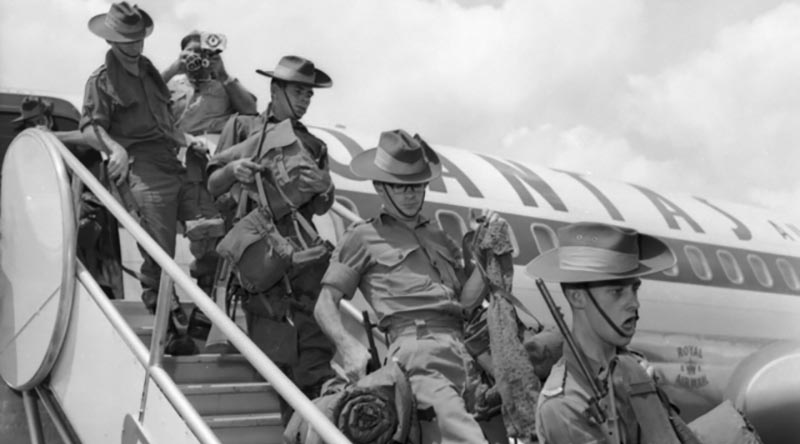 Australian troops disembark a Qantas aircraft to start their tour of duty in Vietnam, at Saigon Airport, April 1966. Photo by WO2 'Billy' Cunneen – AWM CUN/66/0357/VN