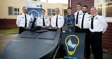 Aircraftman Max Tesoriero (centre) and project manager Sub Lieutenant Ben Jackson (far left) with senior Navy personnel and the uncrewed surface vessel, Lexcen, which he assisted in developing. Story by Flying Officer Jamie Wallace. Photo by Petty Officer Nina Fogliani.