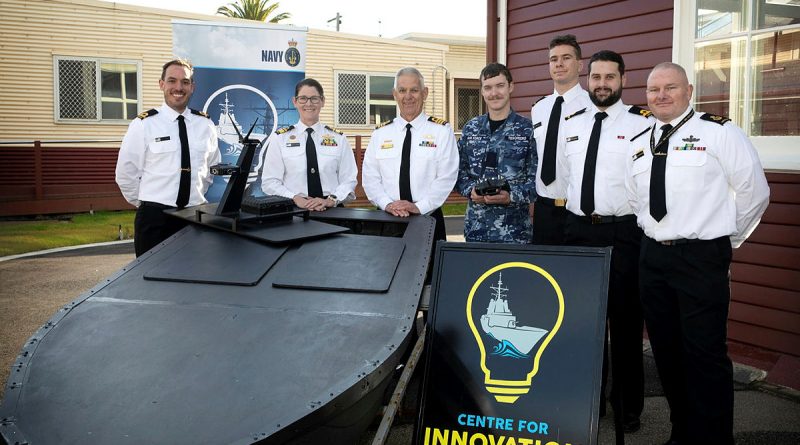 Aircraftman Max Tesoriero (centre) and project manager Sub Lieutenant Ben Jackson (far left) with senior Navy personnel and the uncrewed surface vessel, Lexcen, which he assisted in developing. Story by Flying Officer Jamie Wallace. Photo by Petty Officer Nina Fogliani.