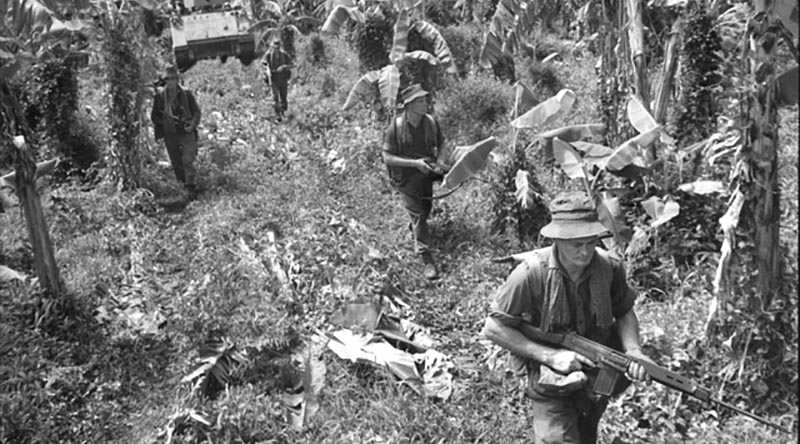 Soldier from the 6th Battalion, Royal Australian Regiment, (6RAR), move into their first operation against the Viet Cong in South Vietnam. The infantry occupied a large Viet Cong village during the mission, code-named Operation Enoggera, in the last week of June 1966. Photo by William 'Billy' Cunneen. AWM CUN/66/0504/VN