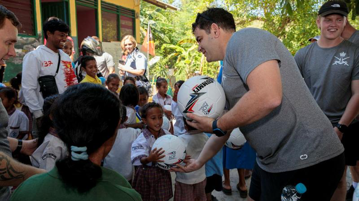 An Australian Army Football Northern Territory team member gives a soccer ball to a child from the Santa Teresinha school in Liquiçá, Timor-Leste, during Indo-Pacific Endeavour 2023. Story by Flight Lieutenant Claire Burnet. Photos by Leading Aircraftman Samuel Miller.