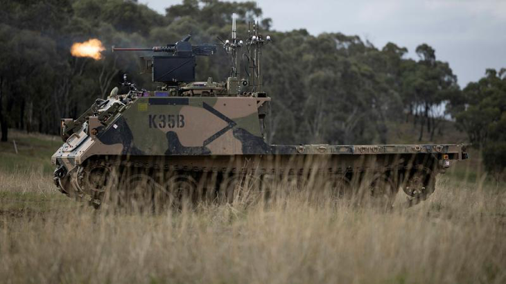 An Australian Army M113AS4 armoured logistics vehicle, fitted with optionally crewed combat vehicle technology and a remote weapon station, fires from a support-by-fire position during a human-machine team exercise. Story and photo by Sergeant Matthew Bickerton.