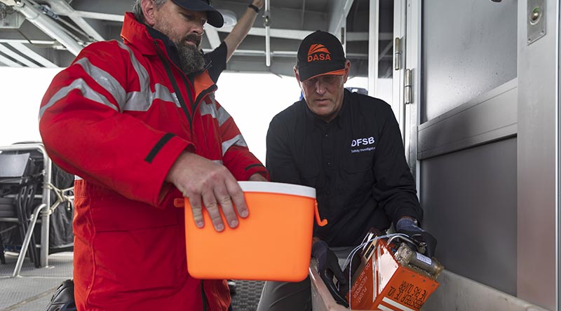 Defence Flight Safety Bureau safety investigator flight data recovery specialist Justin Galbraith (right) and an Australian Transport Safety Bureau investigator prepare the recovered MRH-90 Taipan voice and flight data recorder for transport at Whitsunday Islands (7 August 2023). Photo by Corporal Lisa Sherman.