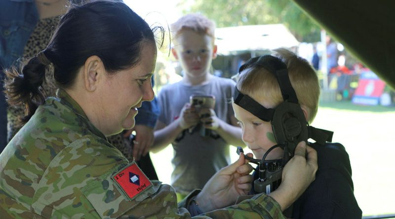 A young boy is fitted with an Army radio during the 31st/42nd Battalion, the Royal Queensland Regiment, Army Reserve open day. Story by Captain Cath Batch. Photos by Susanna Beyer.