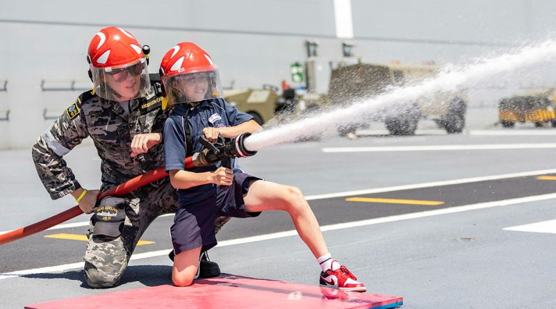 A HMAS Adelaide sailor helps a student from Navy Life Experience with fire hose operations during the inaugural Navy Life Expo in Sydney. Story by Lieutenant Jonathan Wills. Photos by Able Seaman Lucinda Allanson.