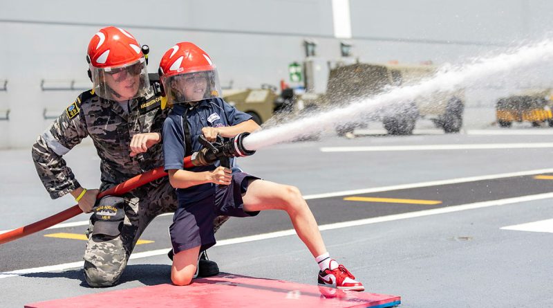 A HMAS Adelaide sailor helps a student from Navy Life Experience with fire hose operations during the inaugural Navy Life Expo in Sydney. Story by Lieutenant Jonathan Wills. Photos by Able Seaman Lucinda Allanson.