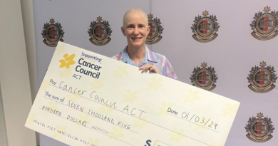Narelle Powers after having her head shaved at Reserve and Cadet Support Headquarters, holding a cheque for $7500. Photo by Emily Egan.