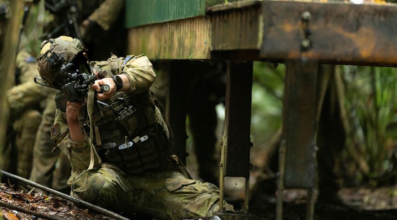 An Australian Army soldier from the 8th/9th Battalion, the Royal Australian Regiment, helps clear a village during Exercise Regional Warfighter in Tully, Queensland. Story by Captain Cody Tsaousis. Photos by Private Alfred Stauder.