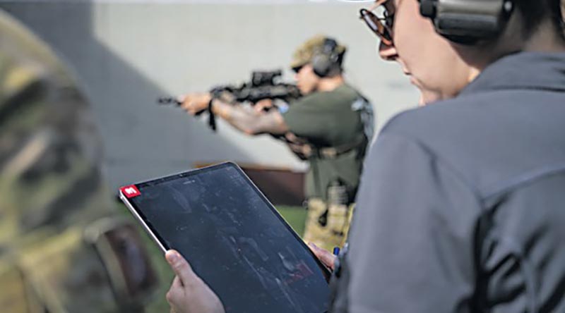 A scientist from La Trobe University checks the readout from a MantisX system attached to a shooter's weapon. Photo by Corporal Michael Rogers.