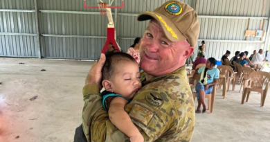 Deputy Mission Commander Pacific Partnership Wing Commander Scott Minchin holds a child during the mission in the Pacific. Story by Corporal Jacob Joseph.