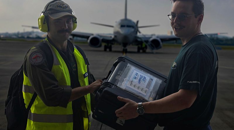 Royal Australian Air Force Flying Officer Eric Morant and Leading Aircraftman Lachlan McAndrew exchange mission data from the P-8A during Operation Argos at Kadena Air Base, Japan. Story and photos by Corporal Luke Bellman.