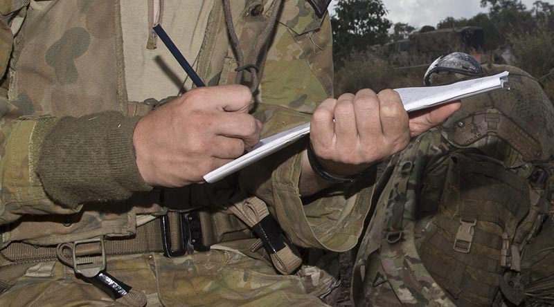 An Aussie soldier writing in the field. Cropped from larger image by Corporal David Cotton.