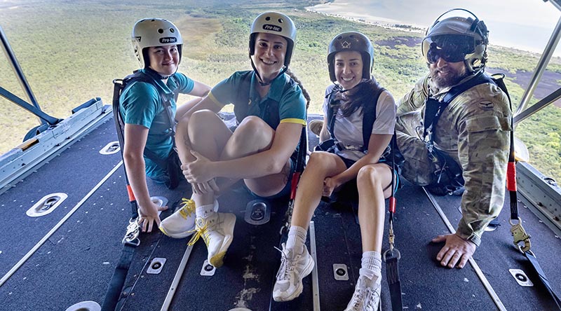 Australian Olympians Haylie Powell and Natalya Diehm, Australian Olympic Committee member Melissa Romer, and Senior Indigenous Liaison Officer, Squadron Leader Coen Henry, sit on the ramp of a Royal Australian Air Force C-130J Hercules during Exercise Christmas Hop 2025, over the Northern Territory. Photo by Leading Aircraftman Campbell Latch.